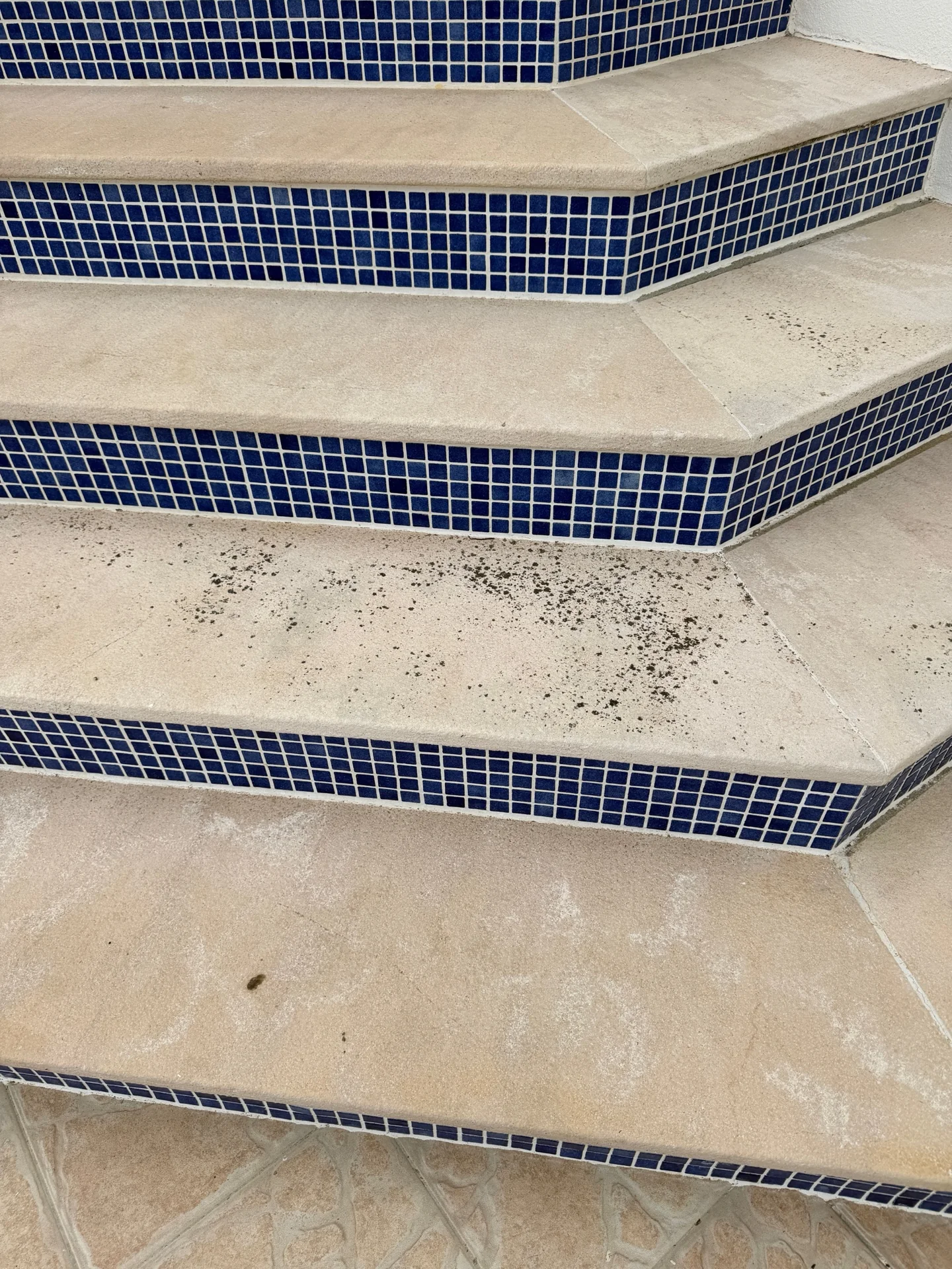 Escadas exteriores claras com espelhos em mosaico azul e pontos escuros nos degraus
